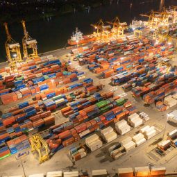 Aerial view of container cargo ship in the export and import business and logistics international goods in urban city. Shipping to the harbour by crane in Bangkok harbour, Thailand at night.